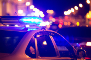 Fototapeta Policja Blue light flasher atop of a police car. City lights on the background.