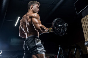 Fototapeta Siłownia A young brutal male athlete is a bodybuilder with a perfect abs, exercising in the gym. Concept - strength, bodybuilding