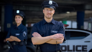 Fototapeta Policja Kind police officers smiling standing near police station, ready to help, order