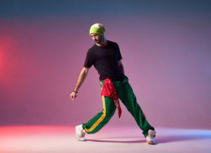 Fototapeta Breakdance Professional breakdancer in motion on studio stage, performing energetic dance, looking down, exercising with strength to win