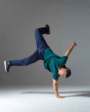 Fototapeta Breakdance Cool guy breakdancer dance on the floor isolated on gray background. Breakdance lessons