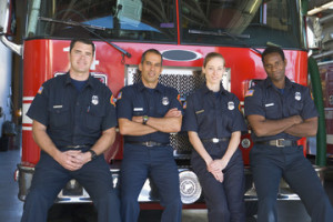 Fototapeta Straż Portrait of firefighters standing by a fire engine