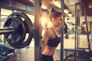 Fototapeta Siłownia Girl in gym doing squats with barbell