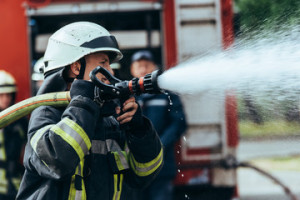Fototapeta Straż selective focus of firefighter with water hose extinguishing fire on street