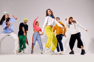 Fototapeta Breakdance Cheerful young teenagers dressed in brightly lighted sportswear dancing actively at hip hop party, gathered together, having